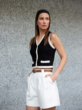 a lady wears a black knitted vest with a white shorts